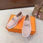 Hermes unisex light pink suede loafers, metal horsebit accent, white textured sole edge.