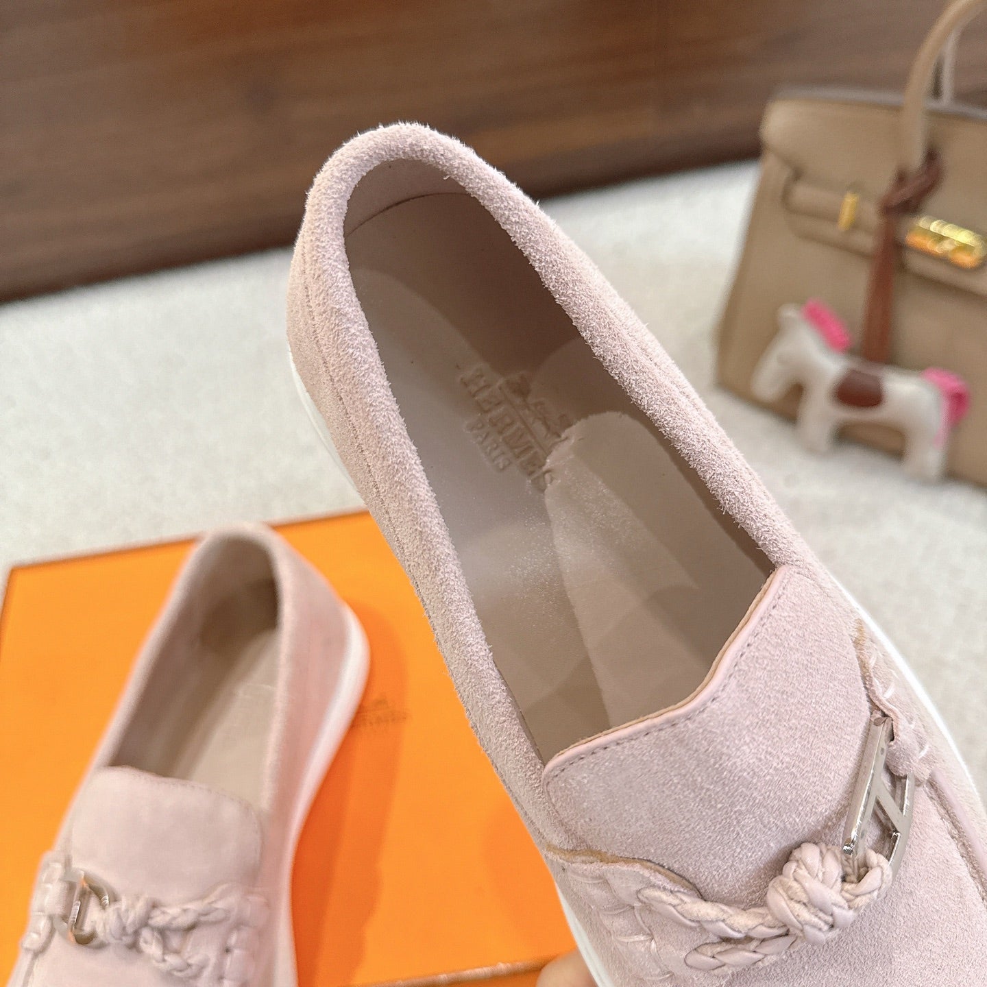 Hermes unisex light pink suede loafers with open collar view and braided horsebit detail.