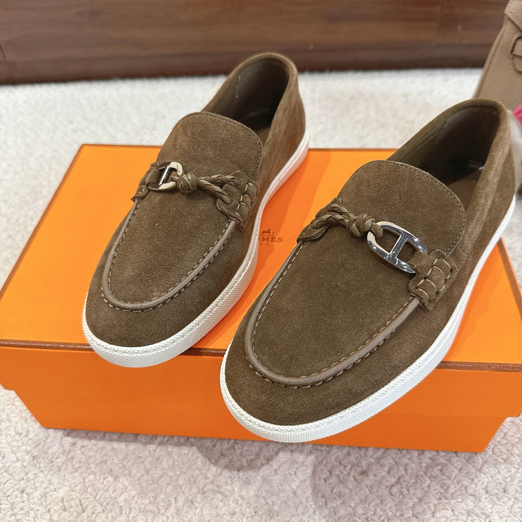 Two dark olive suede slip-on loafers with metal bit hardware and white rubber sole.