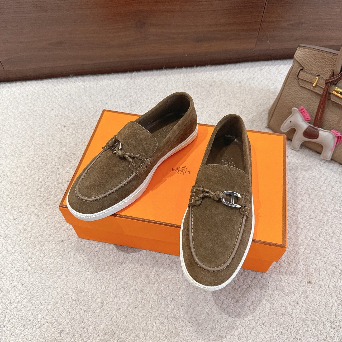 Pair of suede slip-on loafers with metal bit detail and white rubber sole, dark olive.