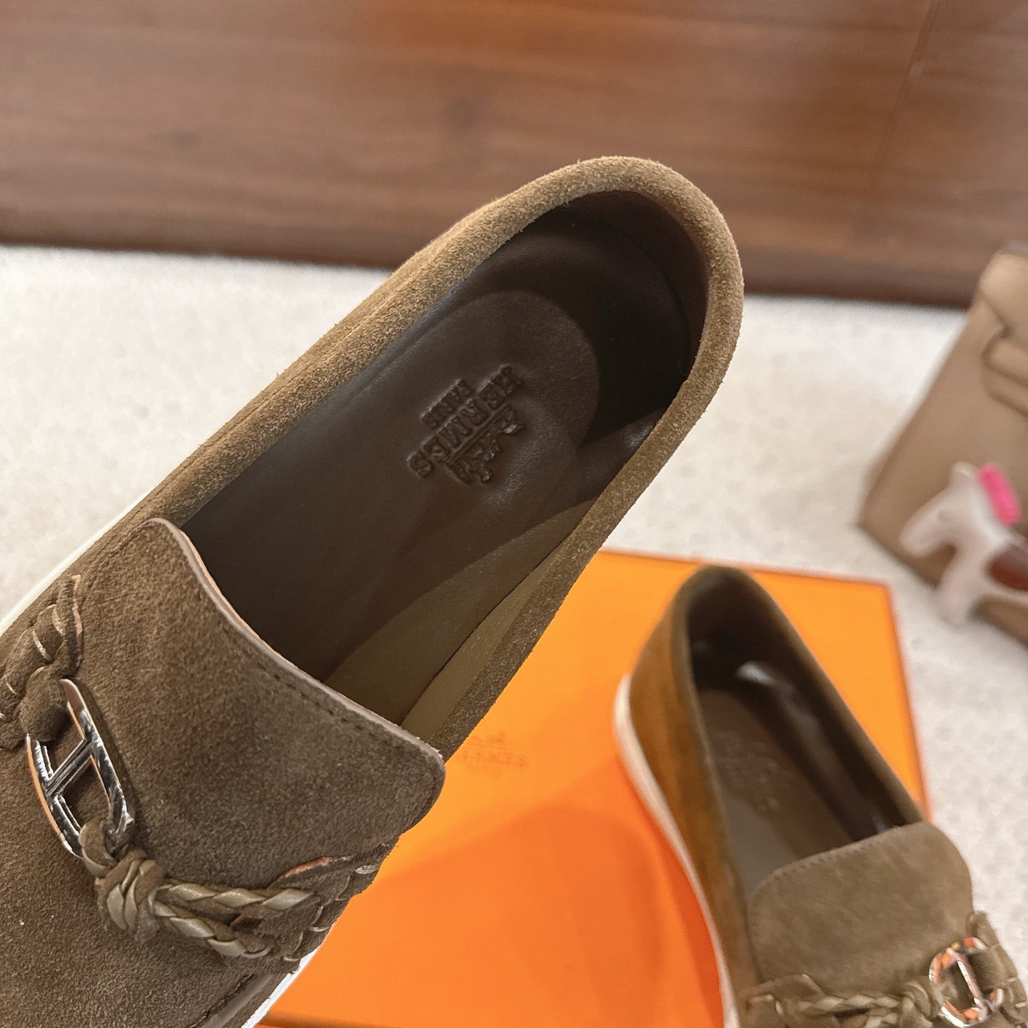 Close-up of dark olive suede loafer interior and metal bit detail, white rubber edge.