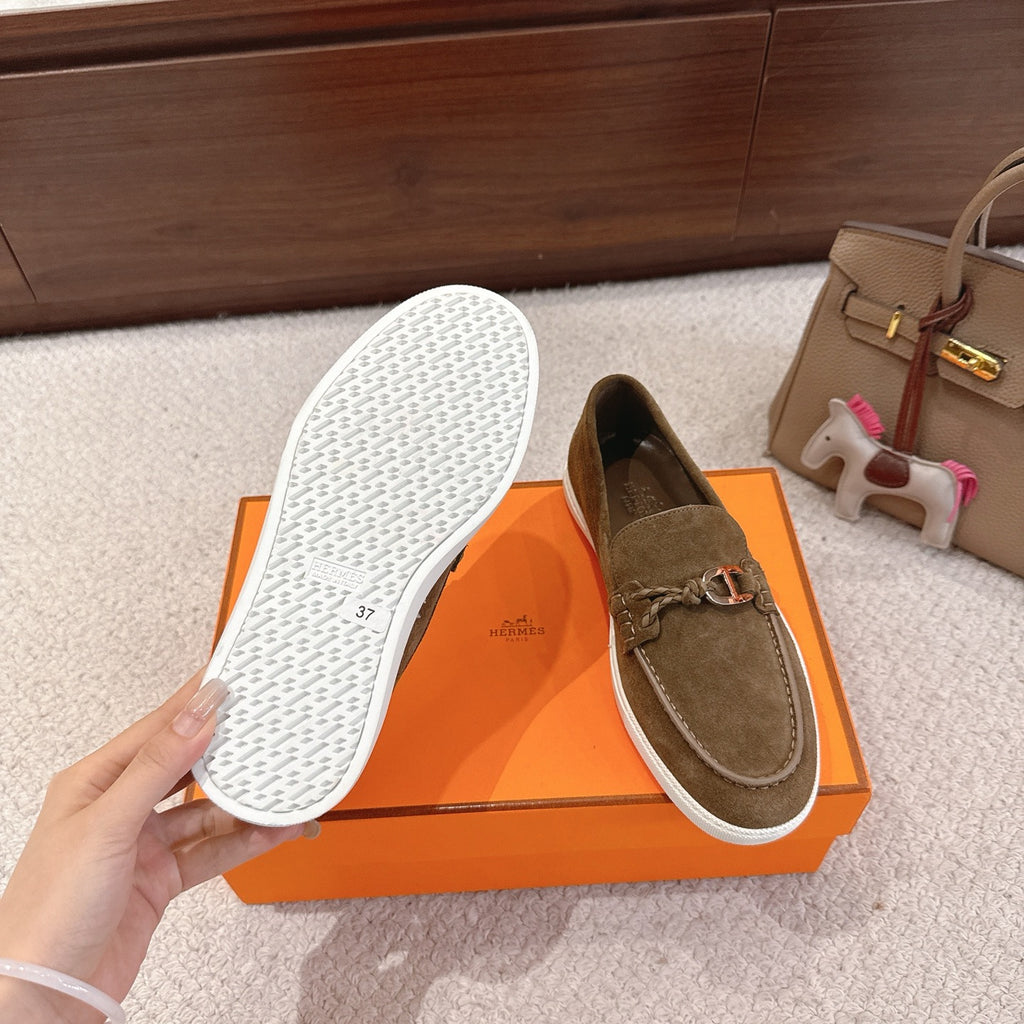 Suede loafer outsole view with textured white sole and dark olive upper; pair on box.