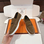 Suede slip-on loafers with metal bit hardware and white rubber sole, dark olive; side view.