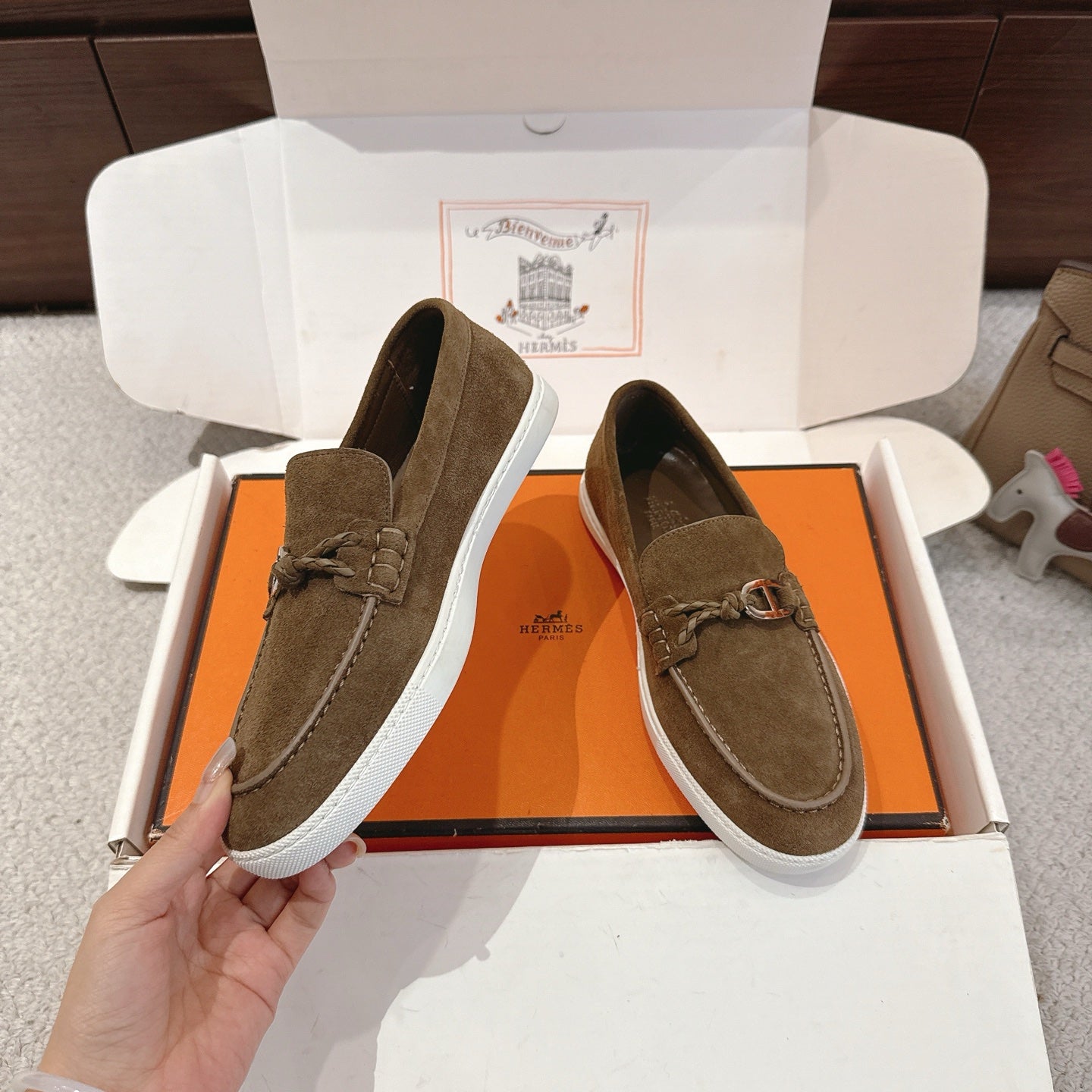 Suede slip-on loafers with metal bit hardware and white rubber sole, dark olive; side view.