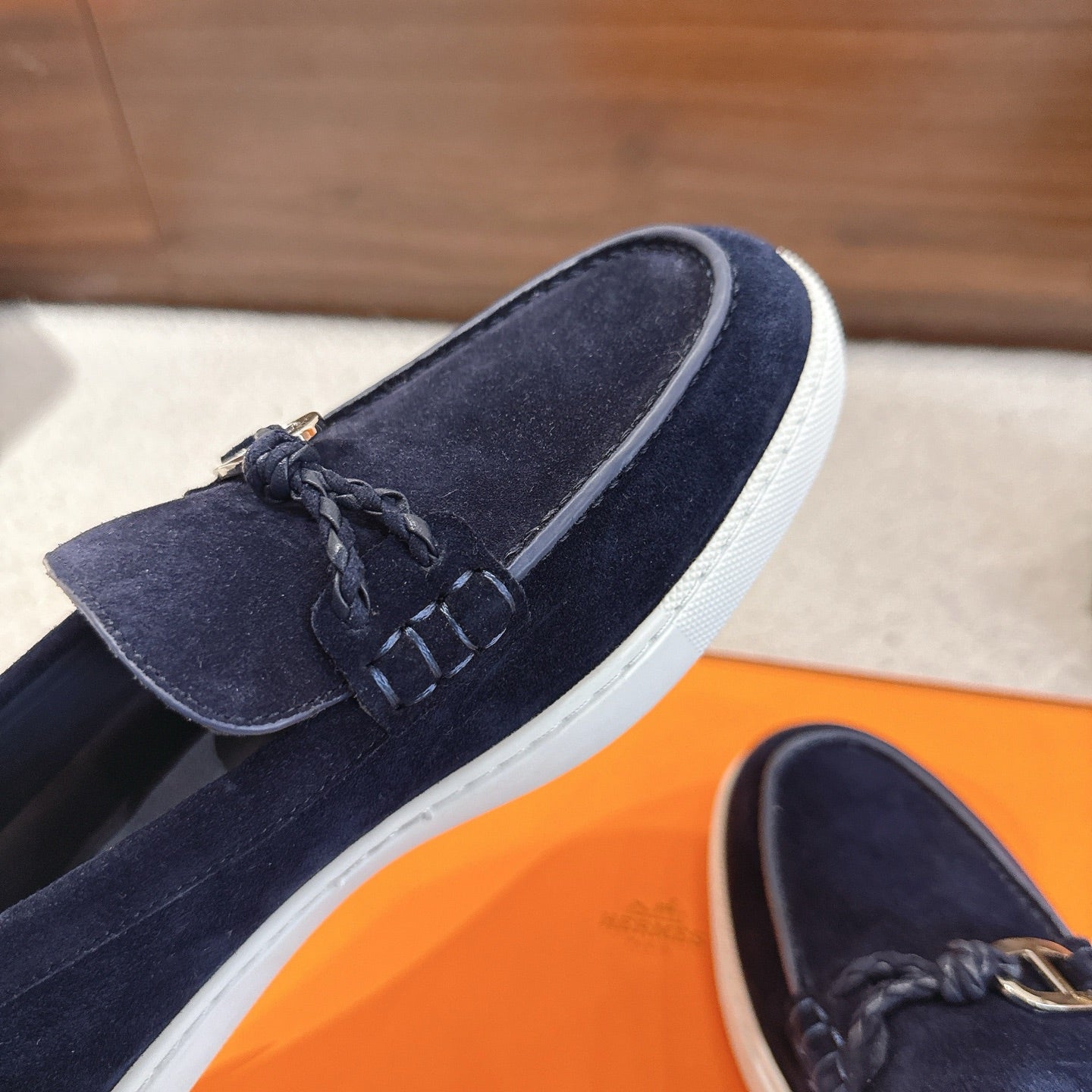 Hermes unisex navy suede loafer close-up, braided lace detail and white sole
