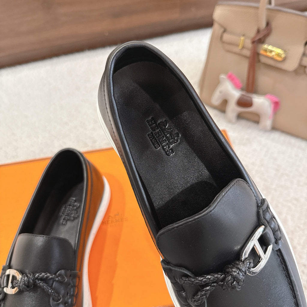 Hermes unisex loafer close-up: dark leather upper with embossed logo and metal buckle