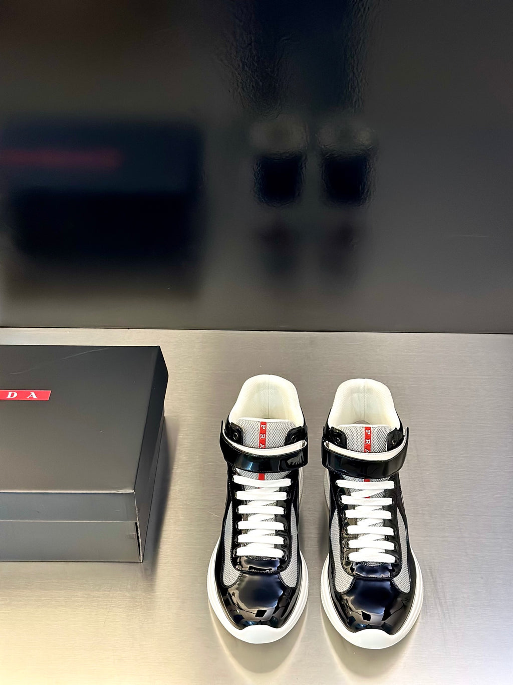 Prada unisex sneakers, black glossy leather, white laces, low top, red tag detail