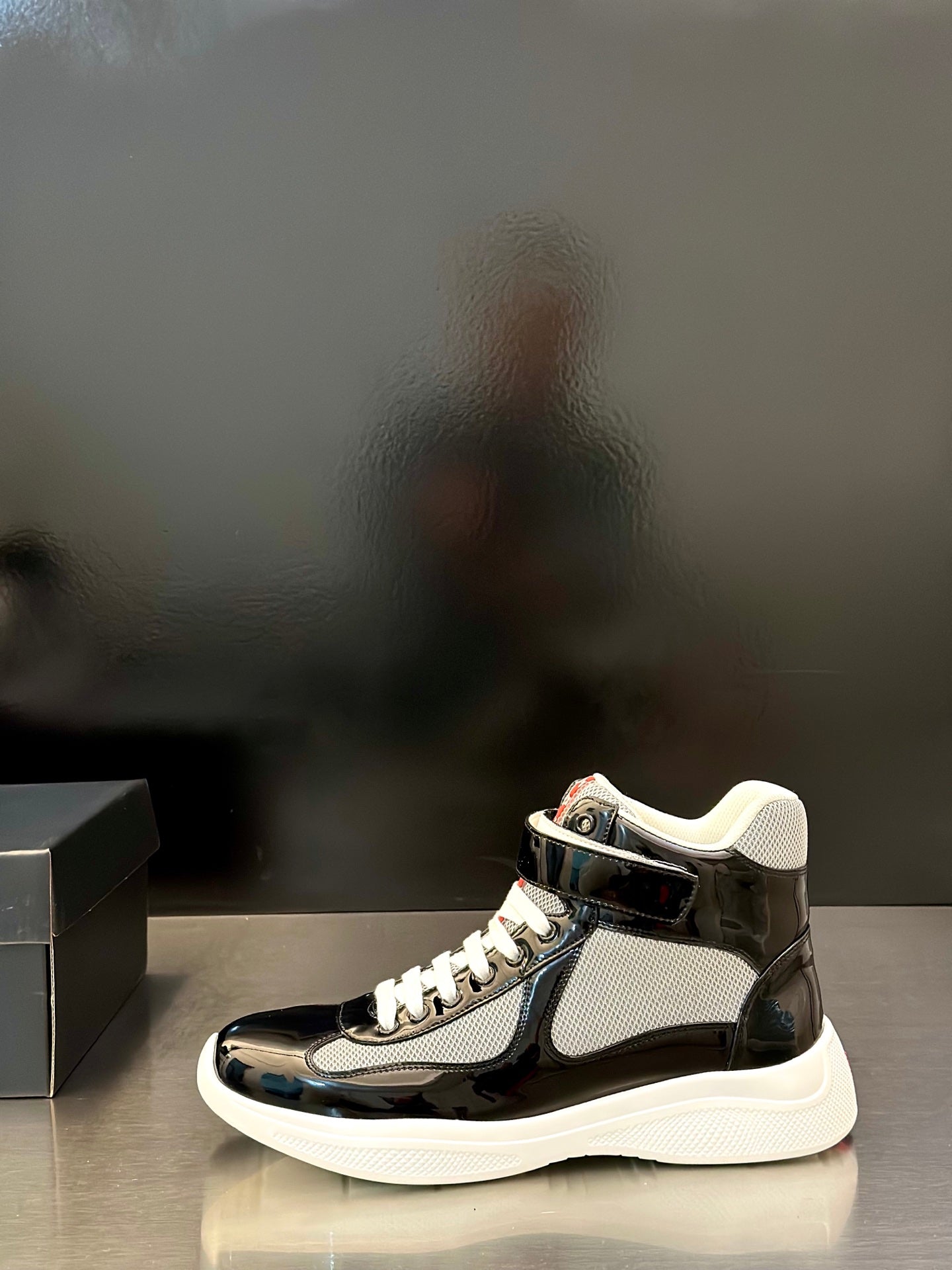 Prada unisex sneakers, black glossy upper with gray knit paneling, white laces, sole