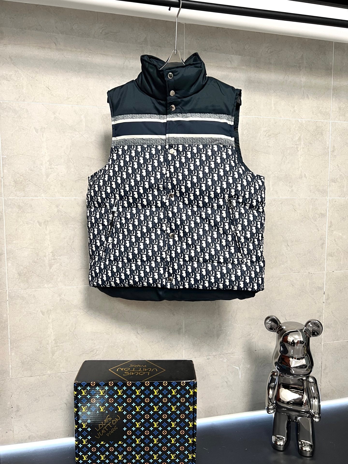 Sleeveless puffer vest with dark collar, white logo print panel, front snap buttons