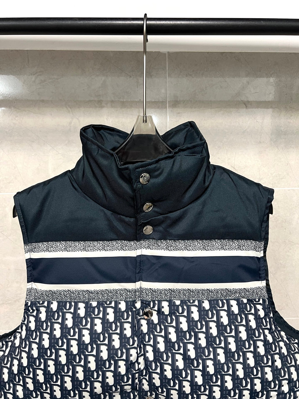 Sleeveless puffer vest with dark hooded collar and white logo stripe across chest
