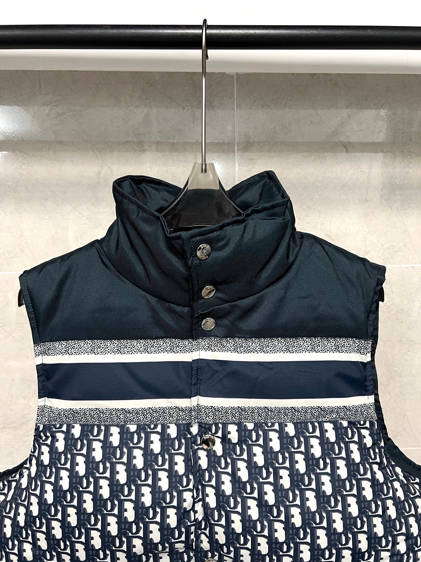 Sleeveless puffer vest with dark hooded collar and white logo stripe across chest