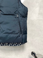 Sleeveless puffer vest with front zipper, dark body, logo trim at hem
