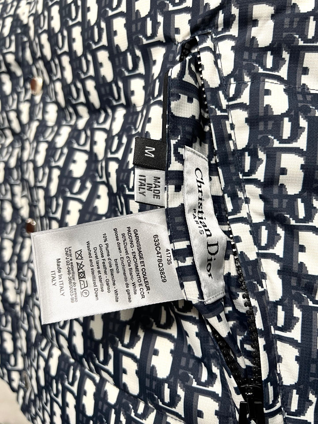 Puffer vest care label and size tag on logo-print fabric