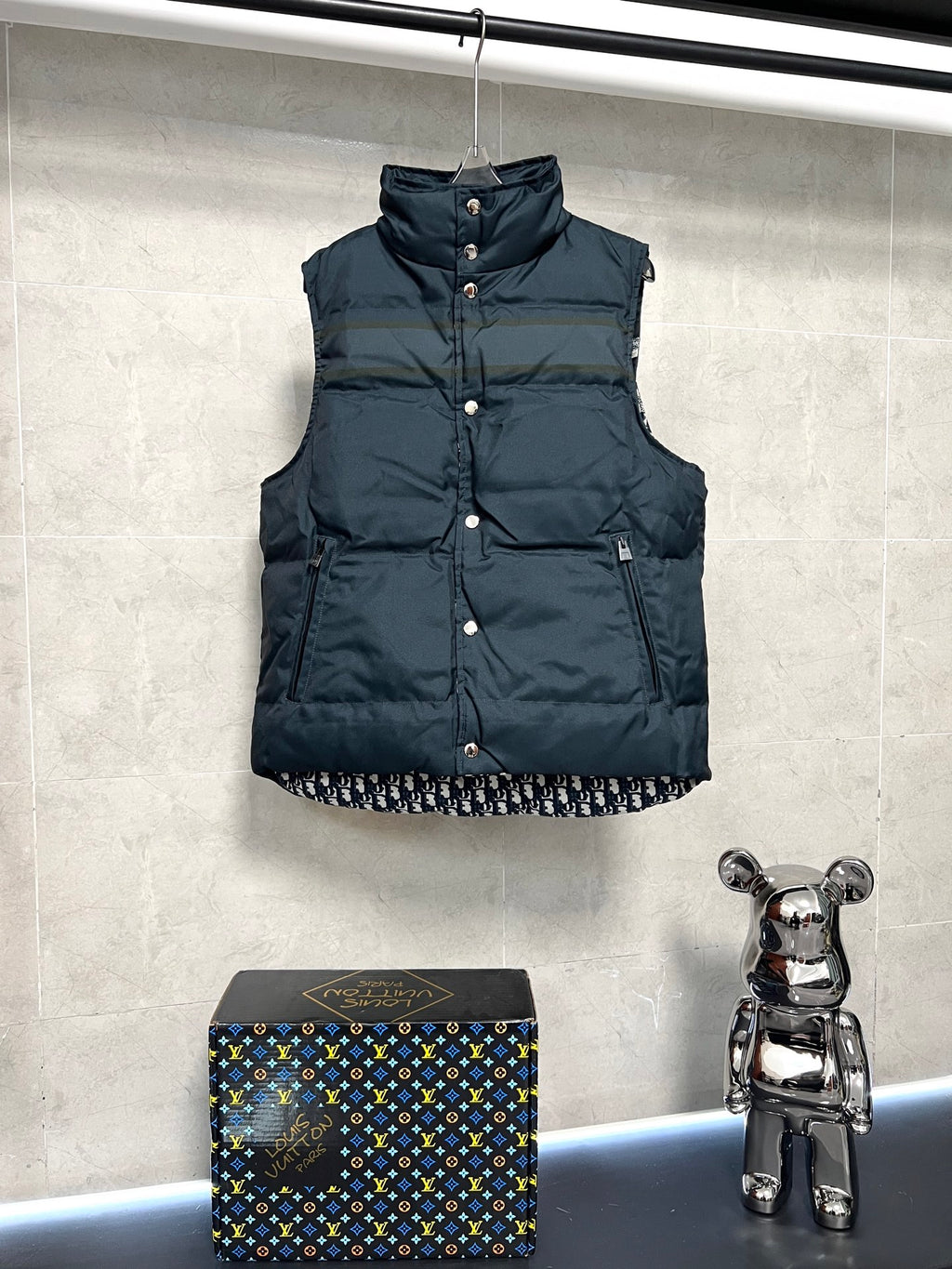 Sleeveless puffer vest with front snap buttons, dark body, logo trim hem
