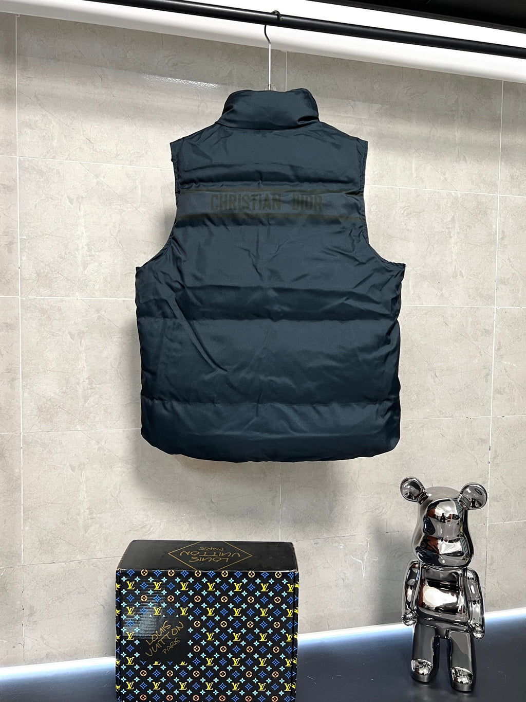 Sleeveless puffer vest back view, dark quilted body, logo trim hem