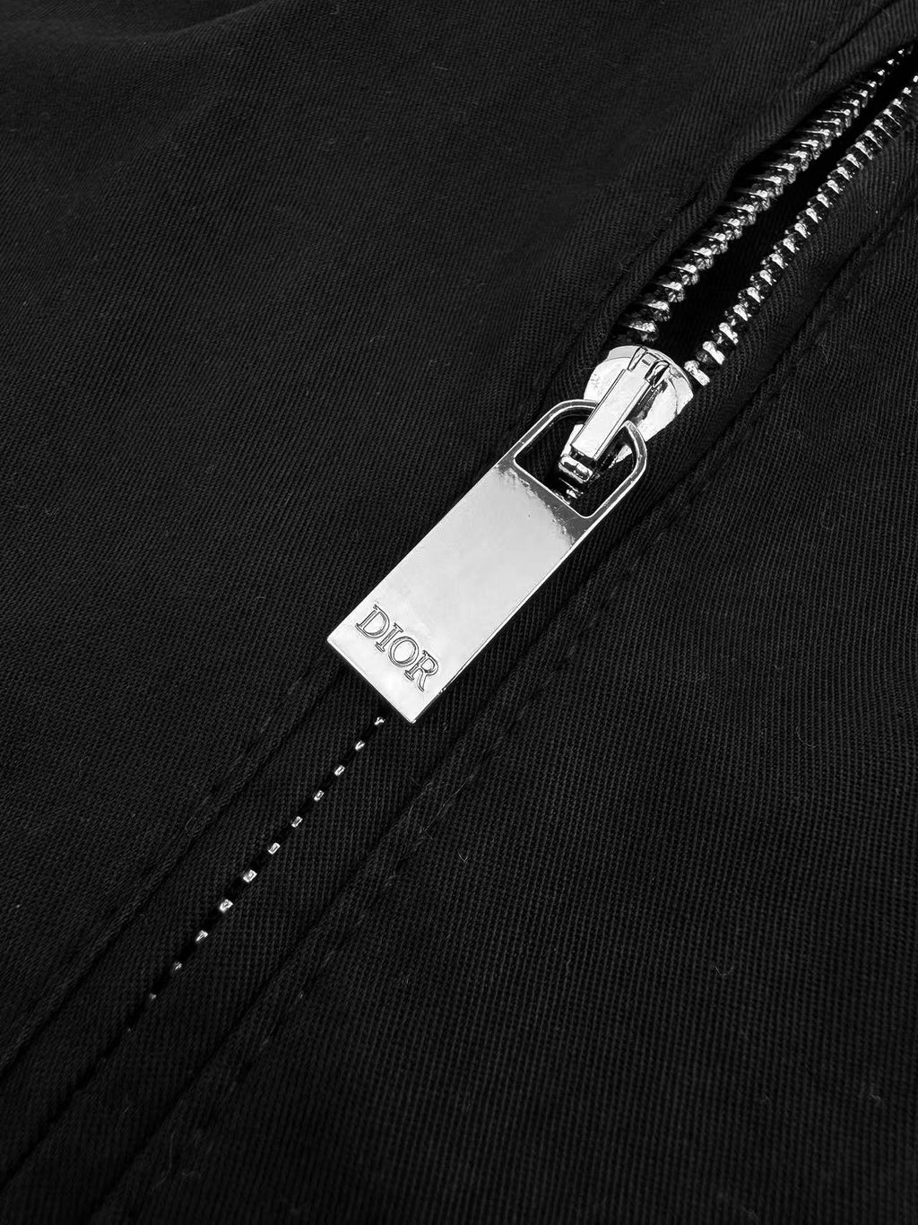 Black Dior pants with metal zipper pull and Dior tag