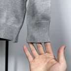 Grey knit sweater sleeve cuff with ribbed hem, shown with hand for size