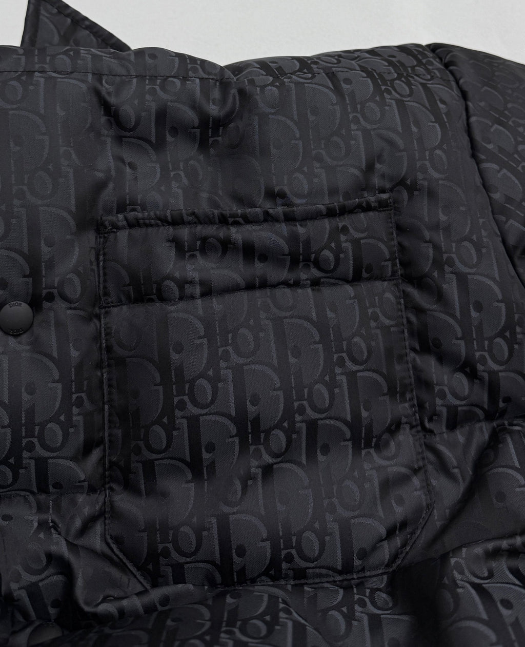 Dior long puffer jacket close-up of chest panel with snap buttons and monogram