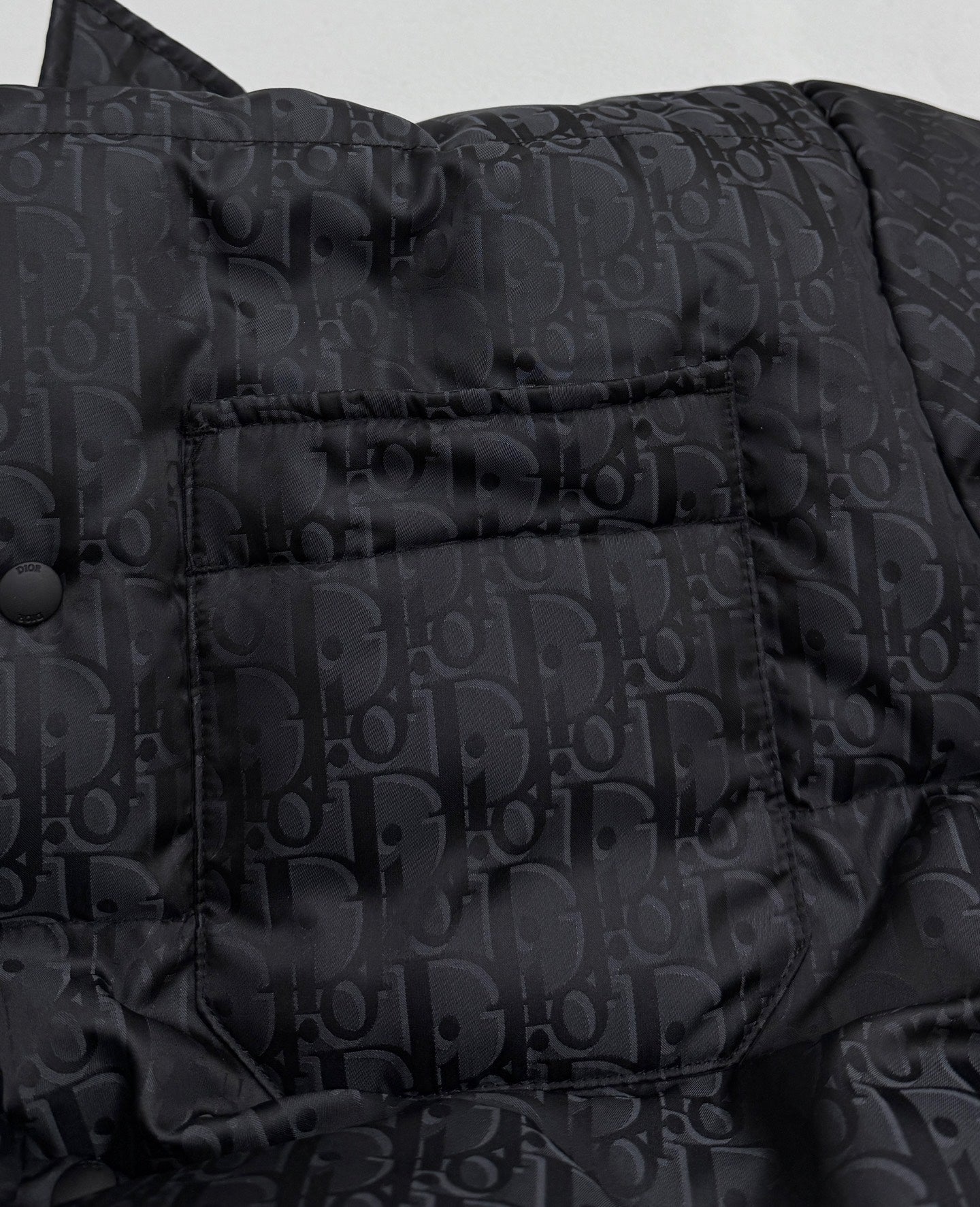 Dior long puffer jacket close-up of chest panel with snap buttons and monogram