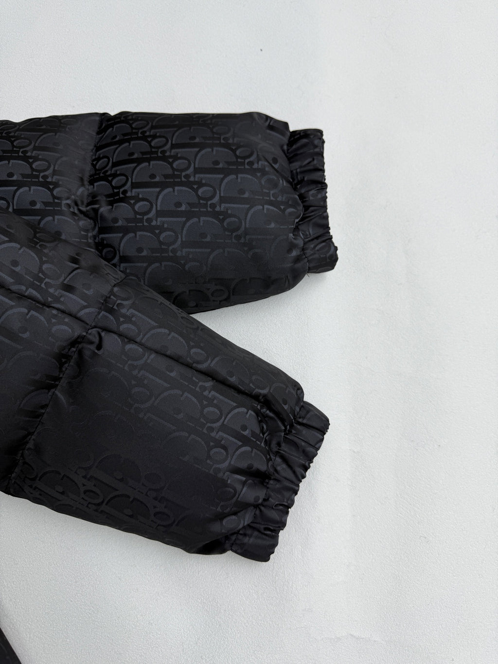 Dior long puffer jacket close-up of sleeves and cuffs in dark monogram fabric