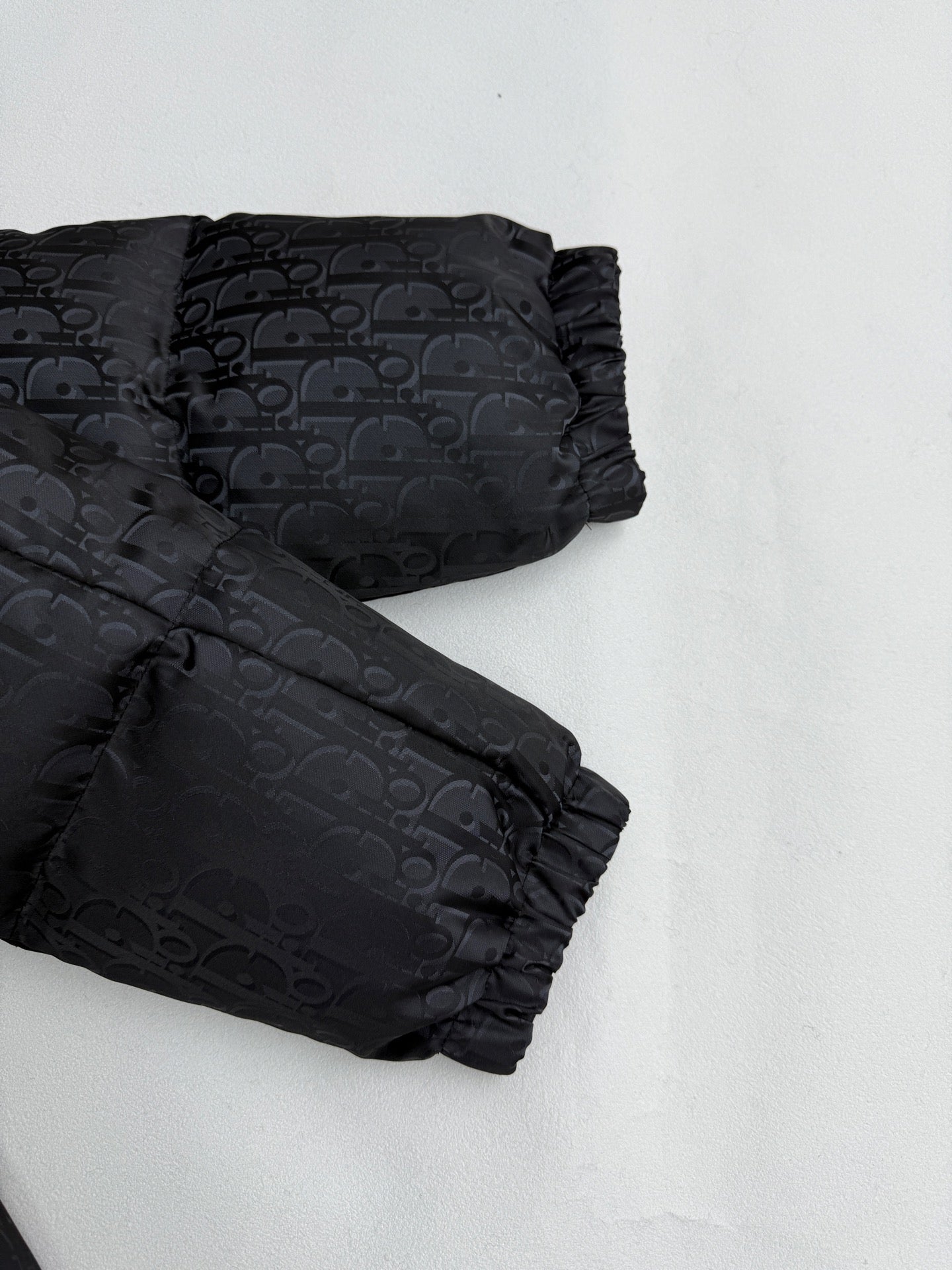 Dior long puffer jacket close-up of sleeves and cuffs in dark monogram fabric