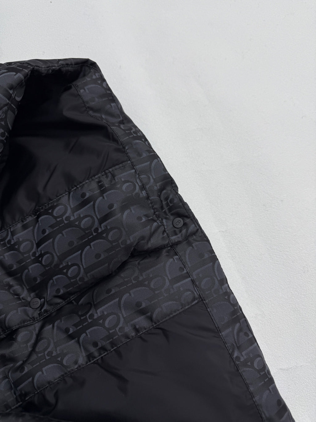 Dior long puffer jacket side panel close-up with dark monogram pattern and stitching