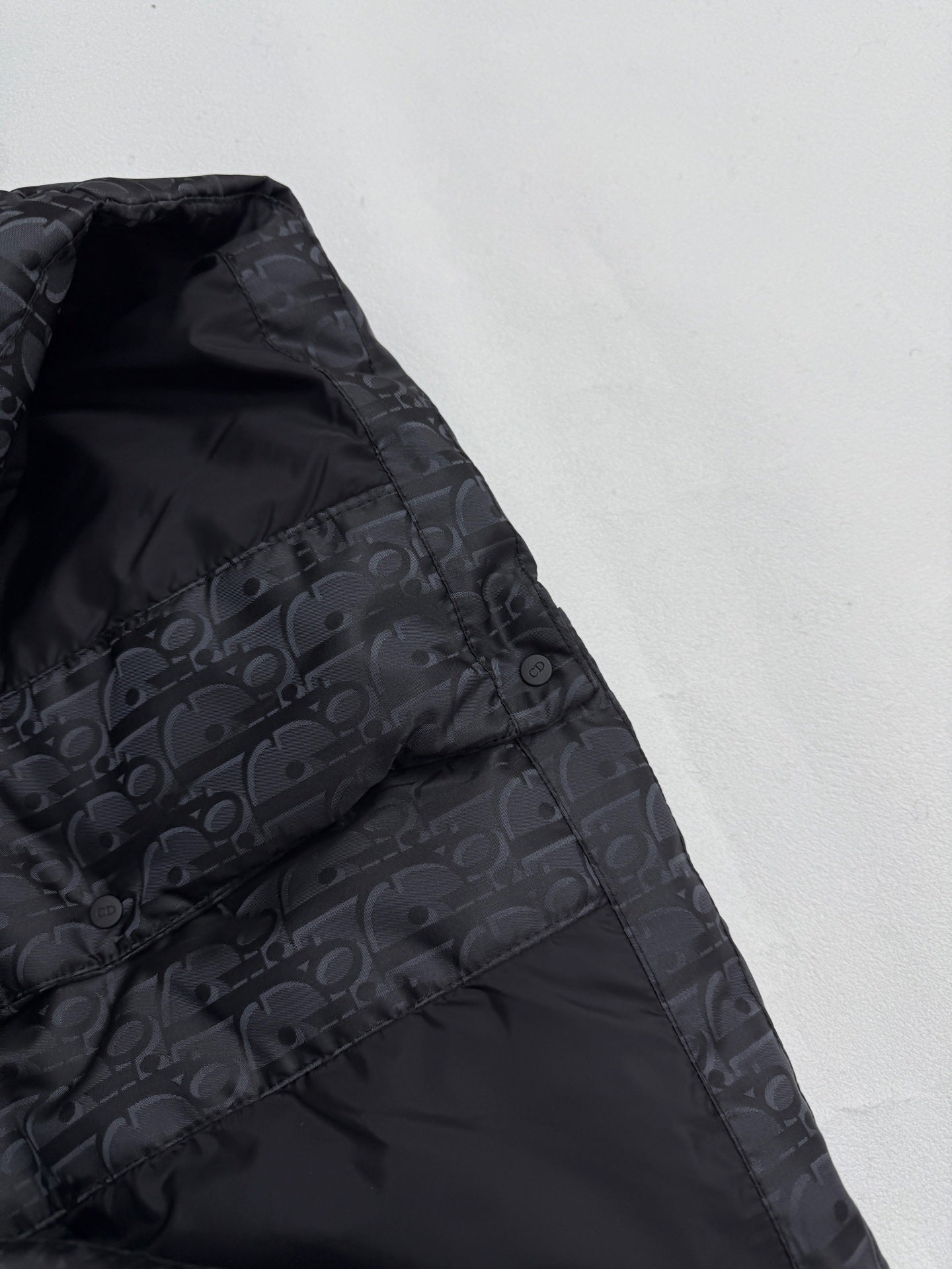 Dior long puffer jacket side panel close-up with dark monogram pattern and stitching