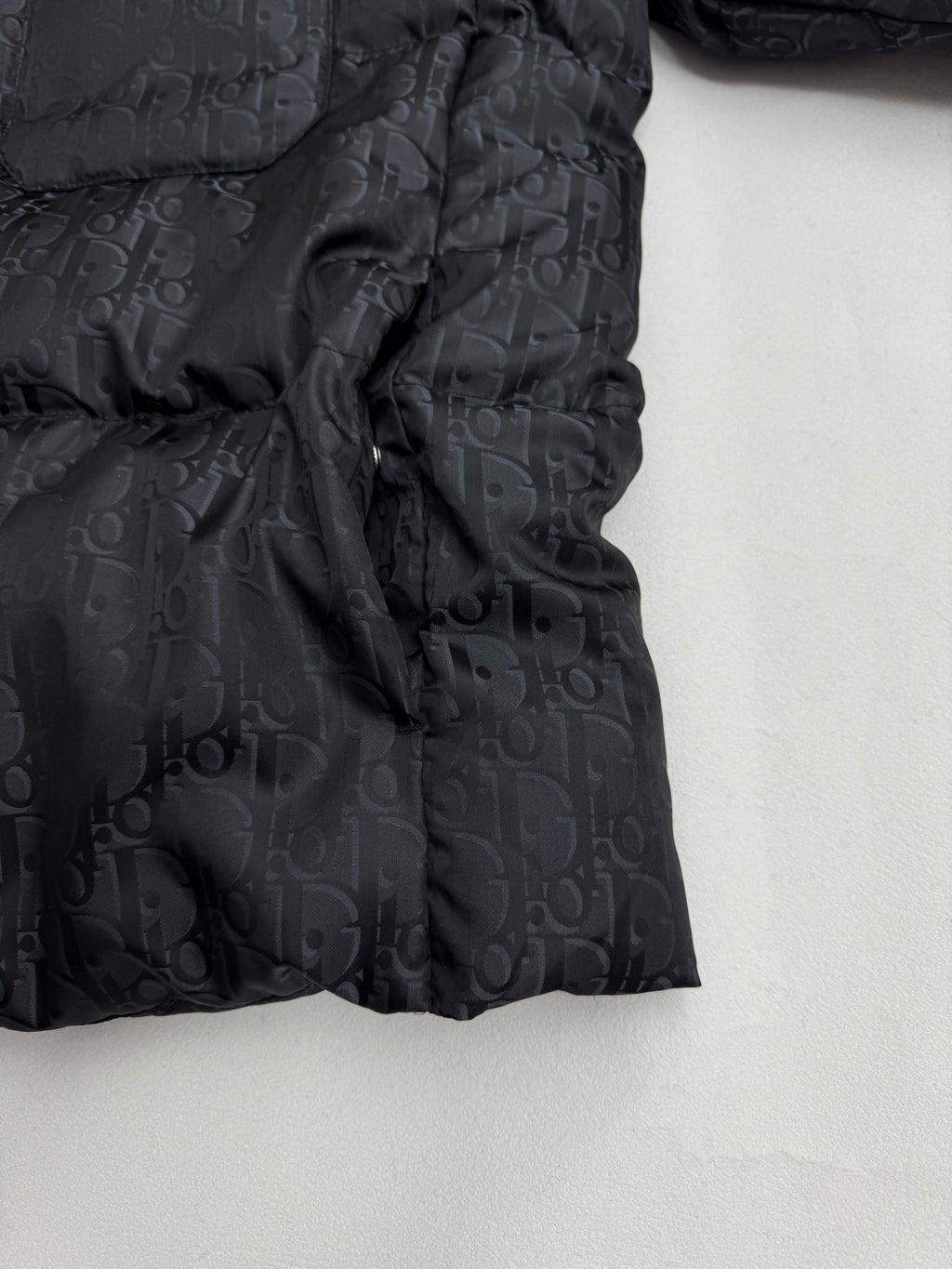 Dior long puffer jacket side view with gathered quilting and dark monogram pattern