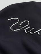 Black hoodie chest panel with large beaded "Vuitton" letter logo