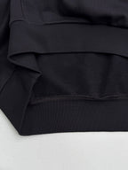 Black hoodie fabric close-up with ribbed waistband and stitched hem