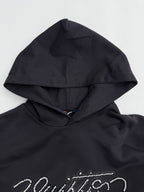 Black hoodie hood close-up with beaded "Vuitton" logo detail across the chest