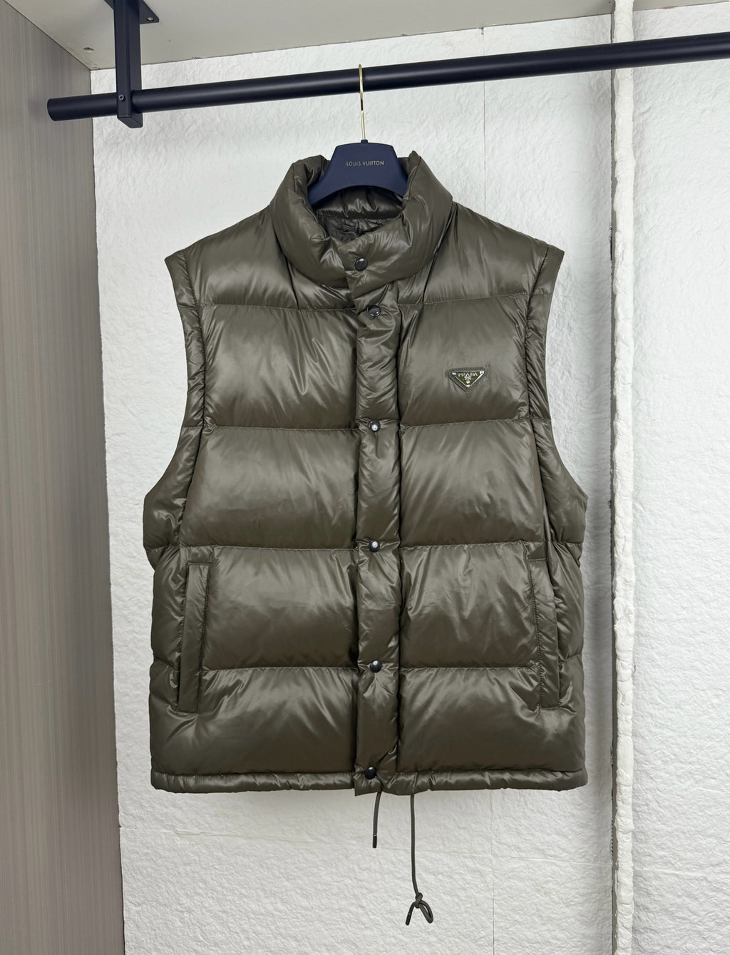Prada long puffer vest in olive with stand collar, button front, and chest logo