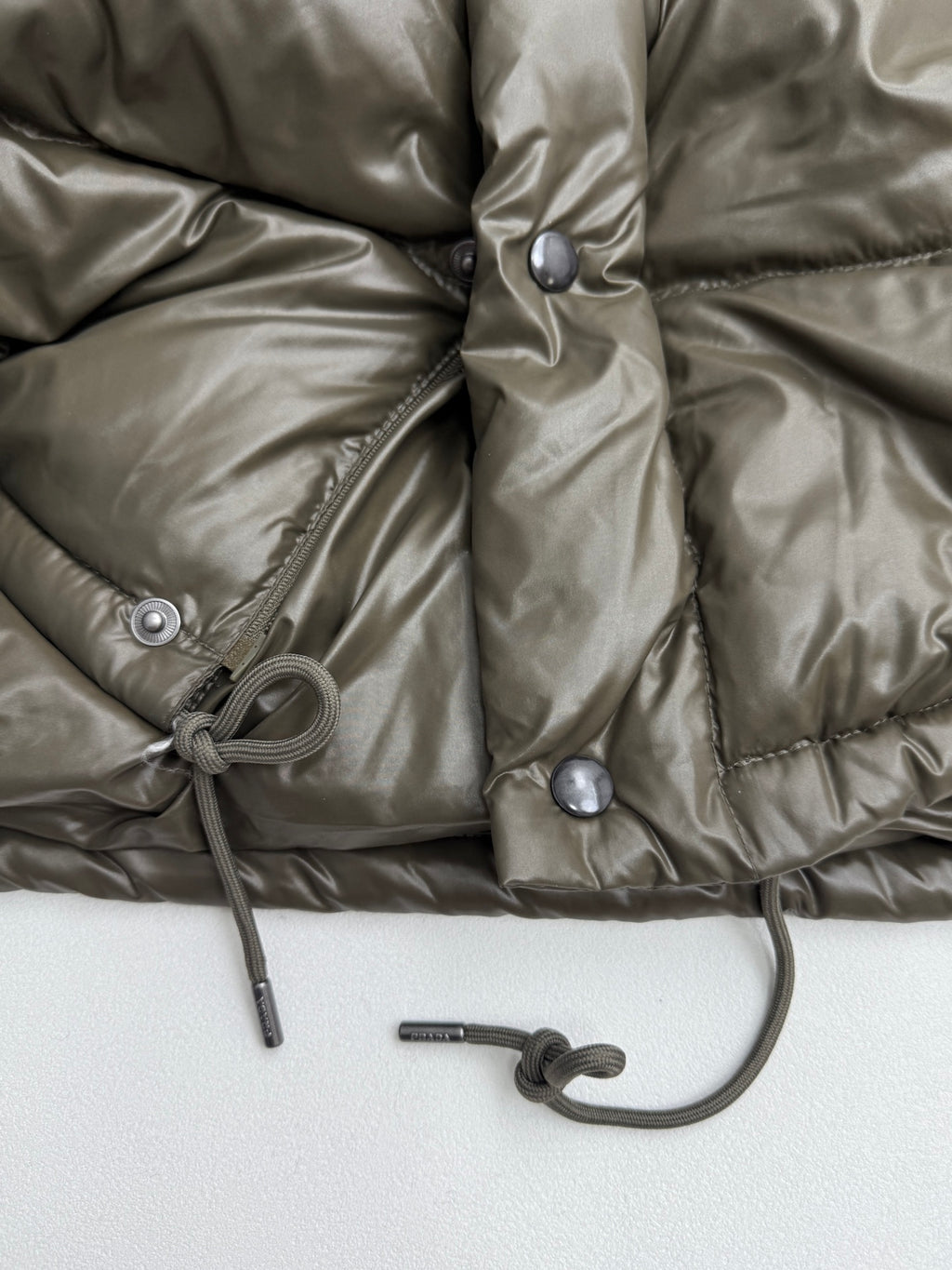Prada puffer jacket front with snap placket and drawstring cord at hem