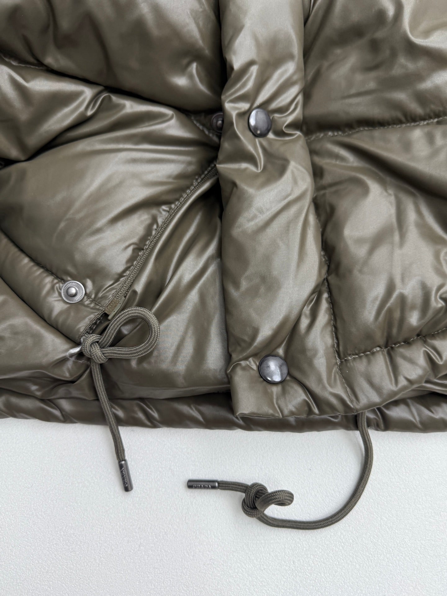 Prada puffer jacket front with snap placket and drawstring cord at hem