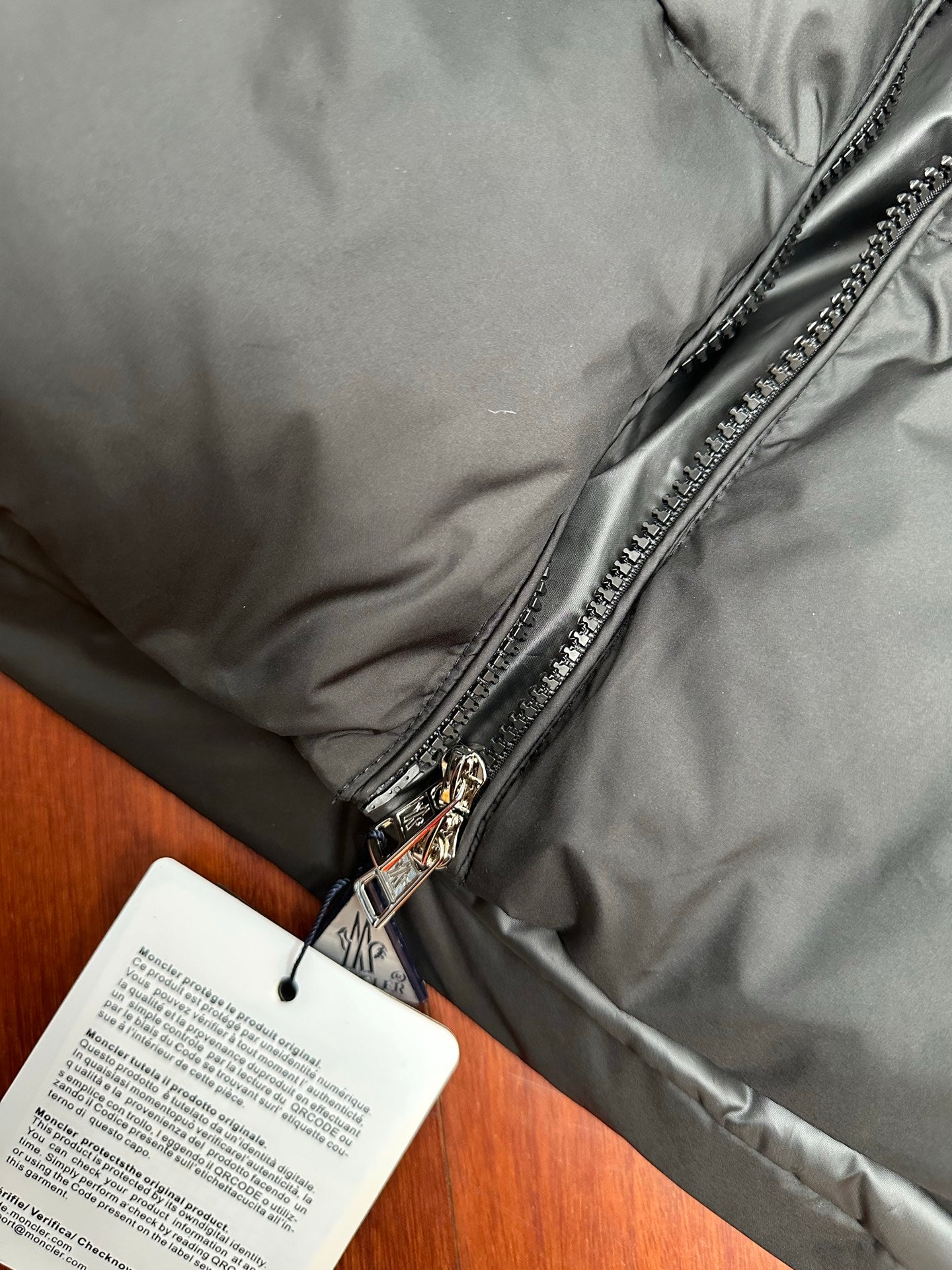 Moncler puffer jacket close-up of front zipper and hanging product card