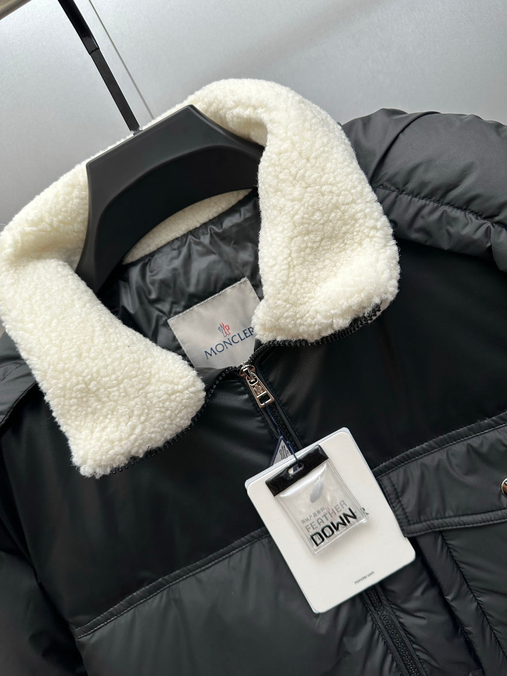 Moncler puffer jacket collar detail with faux shearling lining and hanging tag