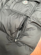Moncler puffer jacket close-up of embroidered logo badge and diagonal zipper seam