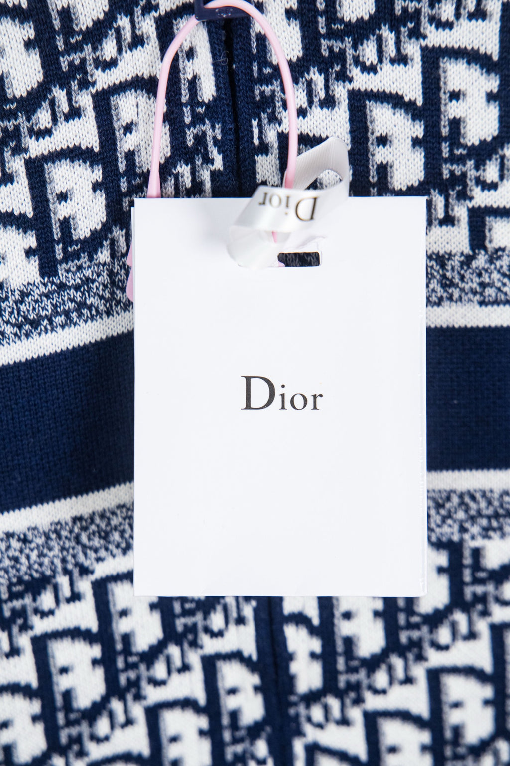 Dior sweater with white hang tag over navy and white monogram knit