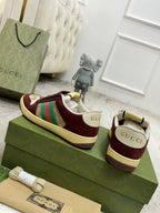 Burgundy Gucci low-top sneakers, side and back views on green retail boxes