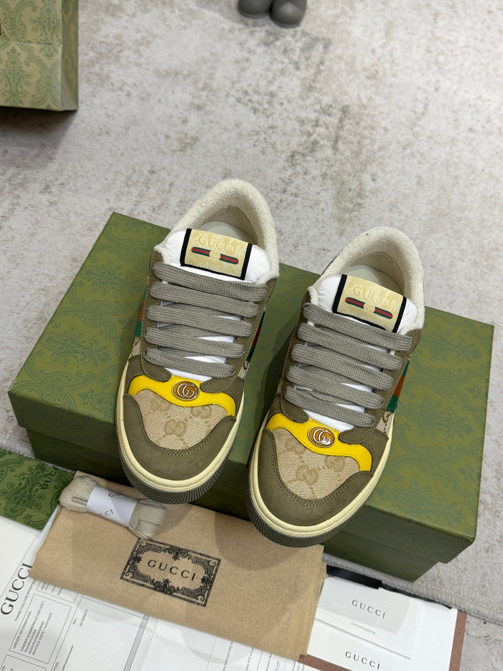Gucci unisex low-top sneakers on green box; gray laces and multicolor stripe panels