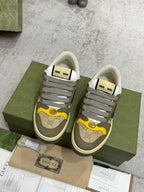 Gucci unisex low-top sneakers on green box; gray laces and multicolor stripe panels