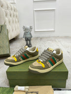 Gucci unisex low-top sneakers pair on green box; gray laces and multicolor stripe