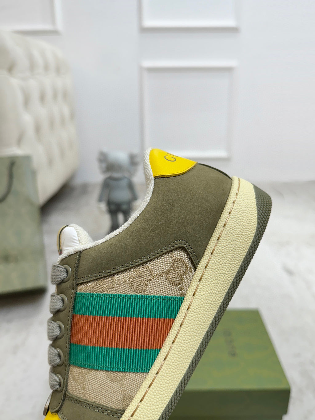Gucci unisex sneaker side view with olive suede, green-red stripe, and yellow collar patch