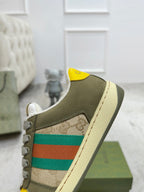 Gucci unisex sneaker side view with olive suede, green-red stripe, and yellow collar patch