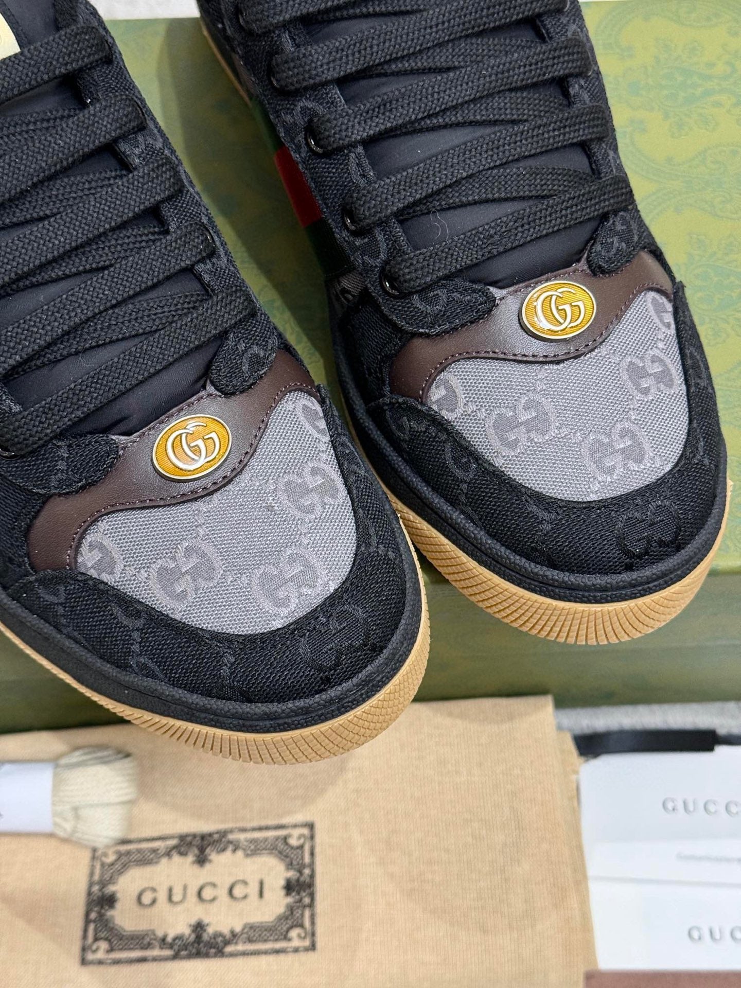 Gucci unisex sneakers close-up: GG logo panels, gold emblem, black laces
