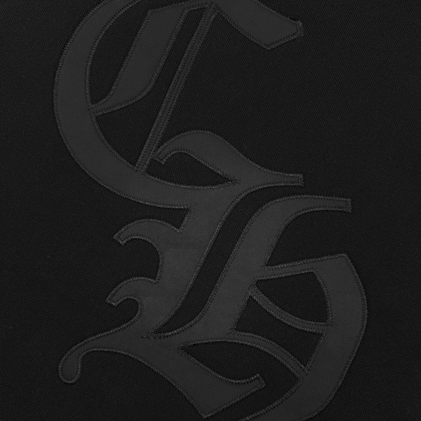 Close-up of large embossed-style logo on black hoodie fabric