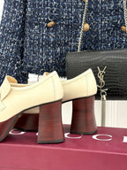 Cream Gucci heeled loafers with metal horsebit detail and dark red block heels, side view