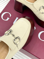 Close-up of cream Gucci loafer with metal horsebit and stitched strap across vamp