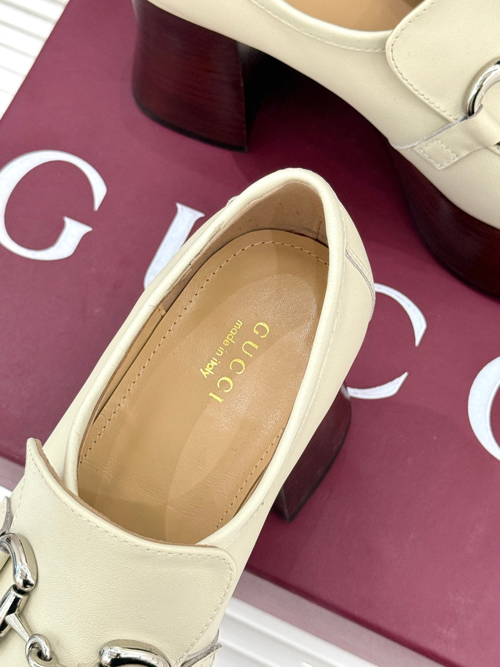 Close-up of cream Gucci loafer interior label and dark red heel