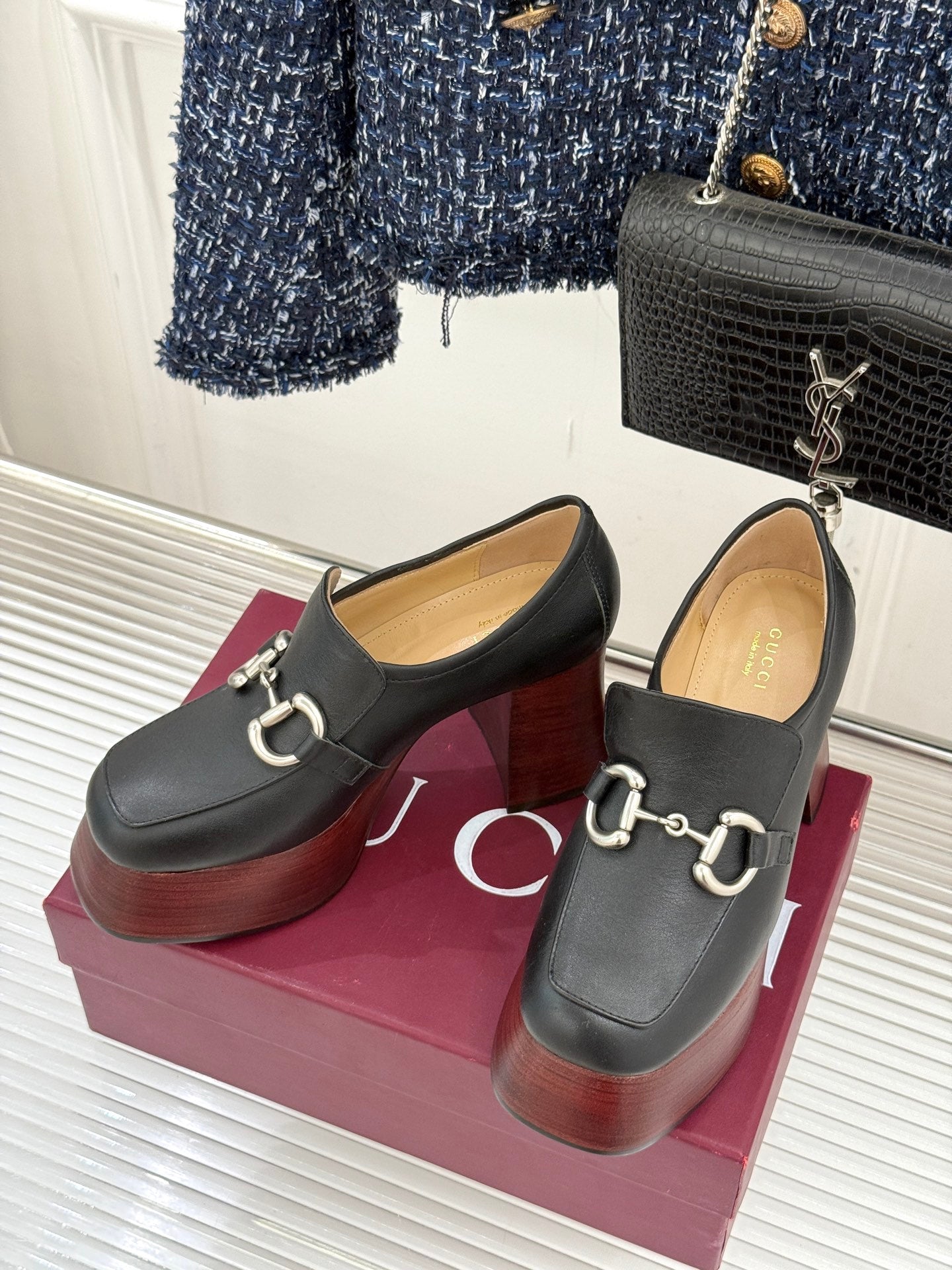 Black leather loafers on chunky wooden platform heels with silver chain detail